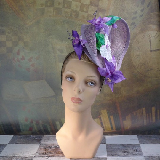 Amethyst Twist hat in shimmering lavendar sinamay headpiece with handmade orchids and hibiscus flowers, handsewn silk bias brim.  In Stock