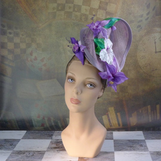 Amethyst Twist hat in shimmering lavendar sinamay headpiece with handmade orchids and hibiscus flowers, handsewn silk bias brim.  In Stock